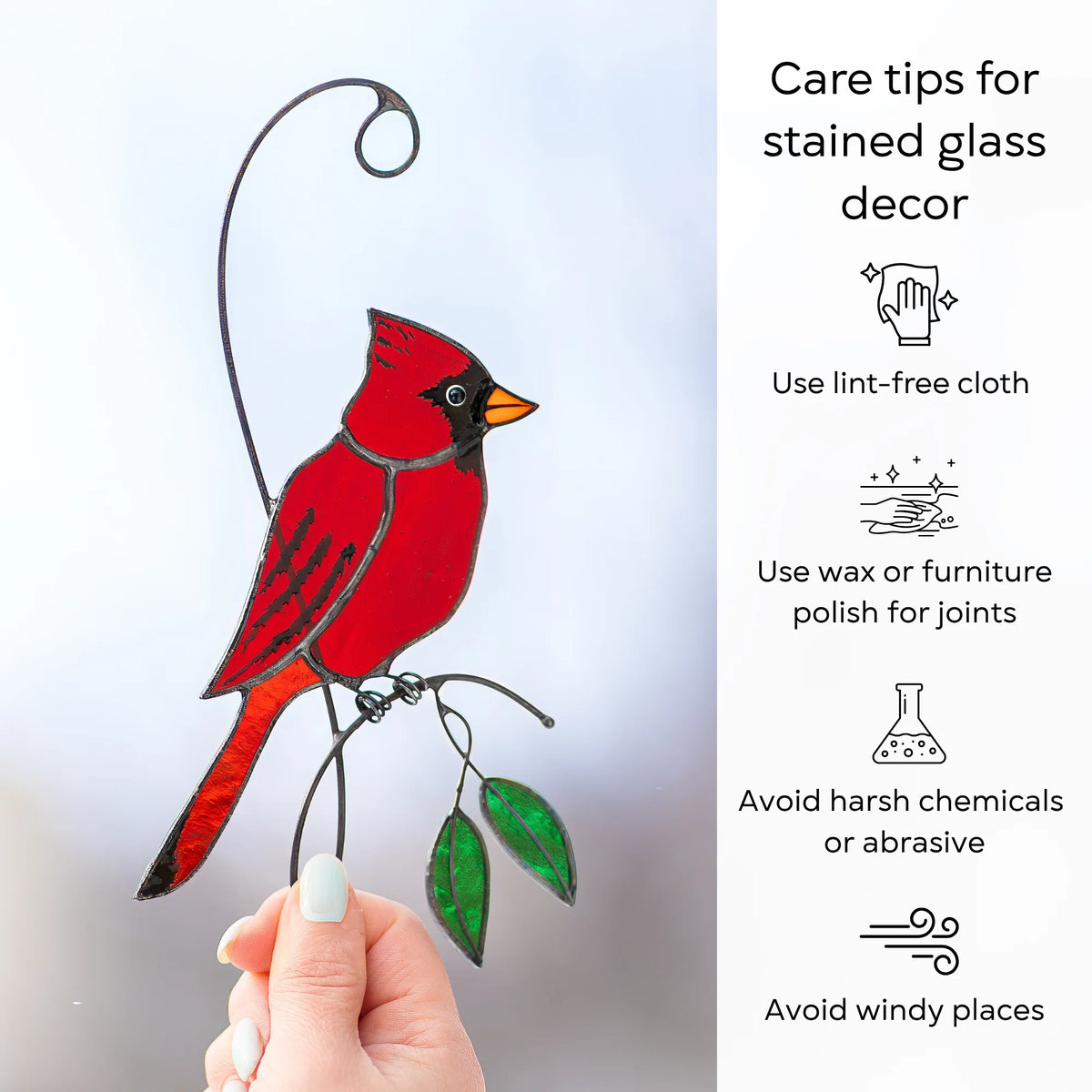 Care tips for a red cardinal stained glass suncatcher held in hand - dust with a lint-free cloth, protect the joints with wax or furniture polish, and avoid harsh chemicals, abrasives and windy places