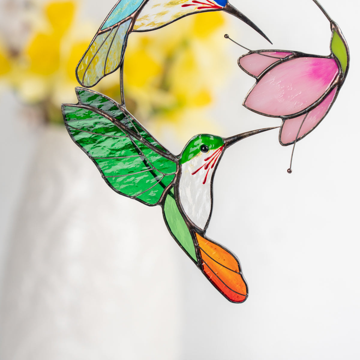 Close-up view of the vivid green hummingbird and pink flower made from stained glass