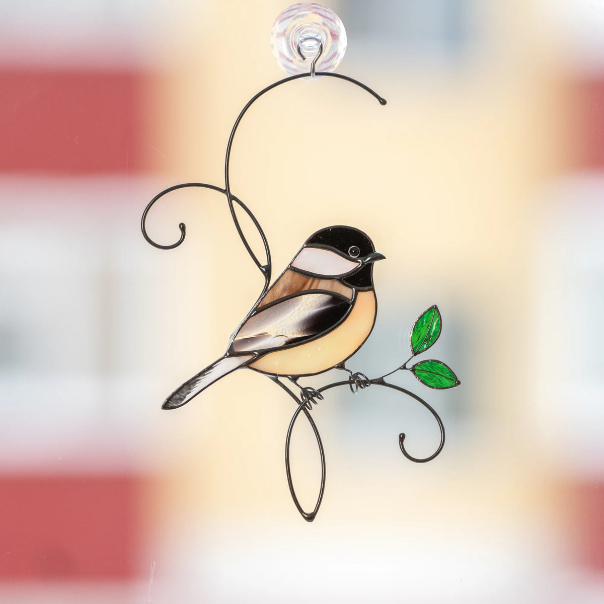 Stained glass chickadee suncatcher held against a blue spring sky with cherry blossoms, black-capped chickadee with a yellow belly on a wire branch - handmade bird window decor and gift