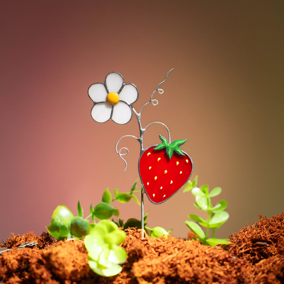 Stained glass flower and strawberry on a brown surface with a blurred background