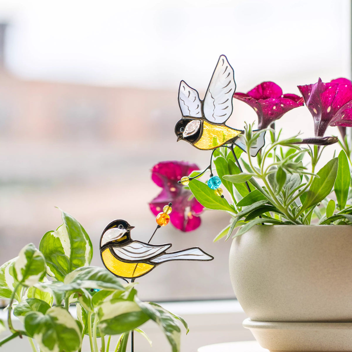 Stained glass birds on a plant with a blurred background