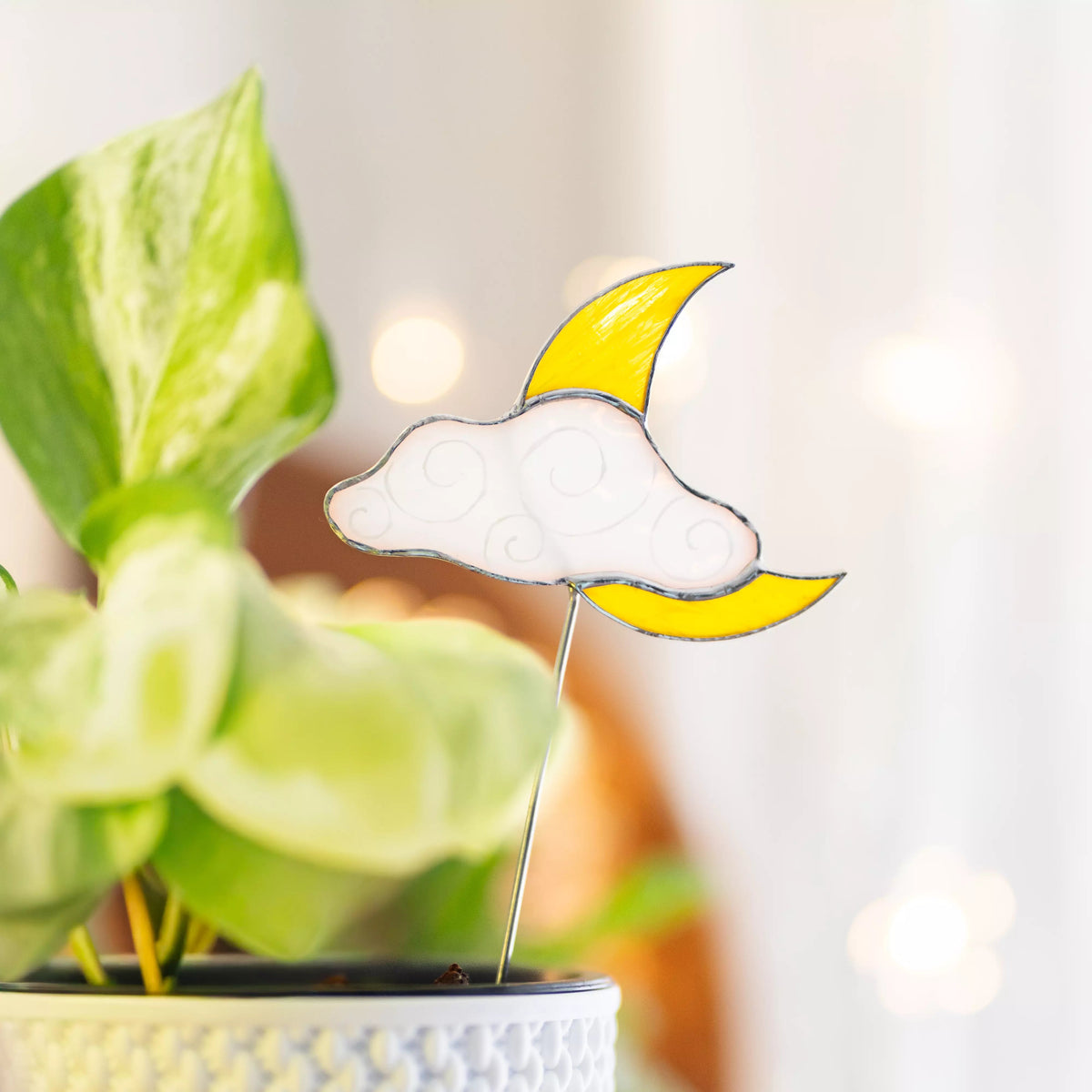 Stained glass moon and cloud plant stake with a blurred plant background