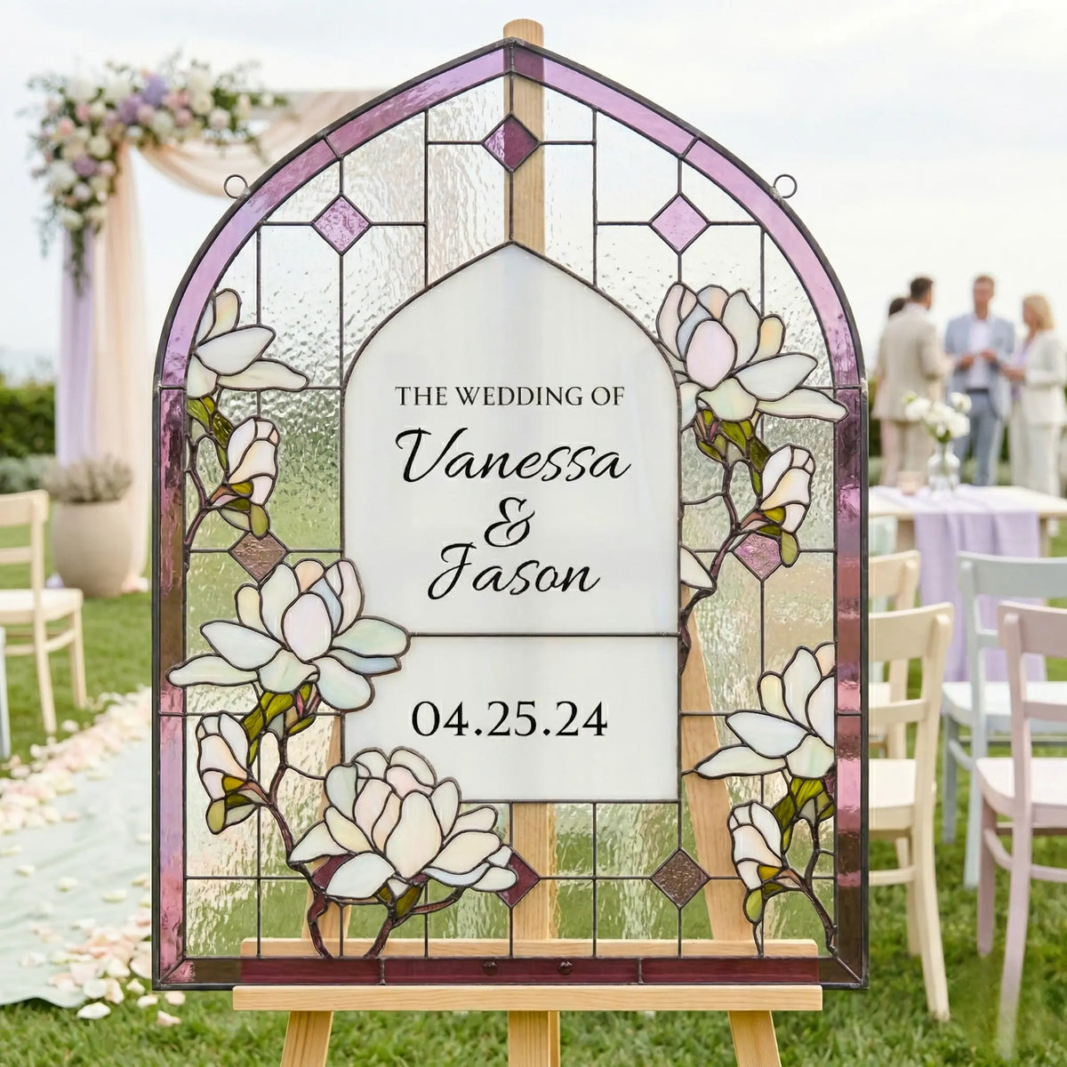 Stained glass wedding sign with floral design and text on an easel outdoors.