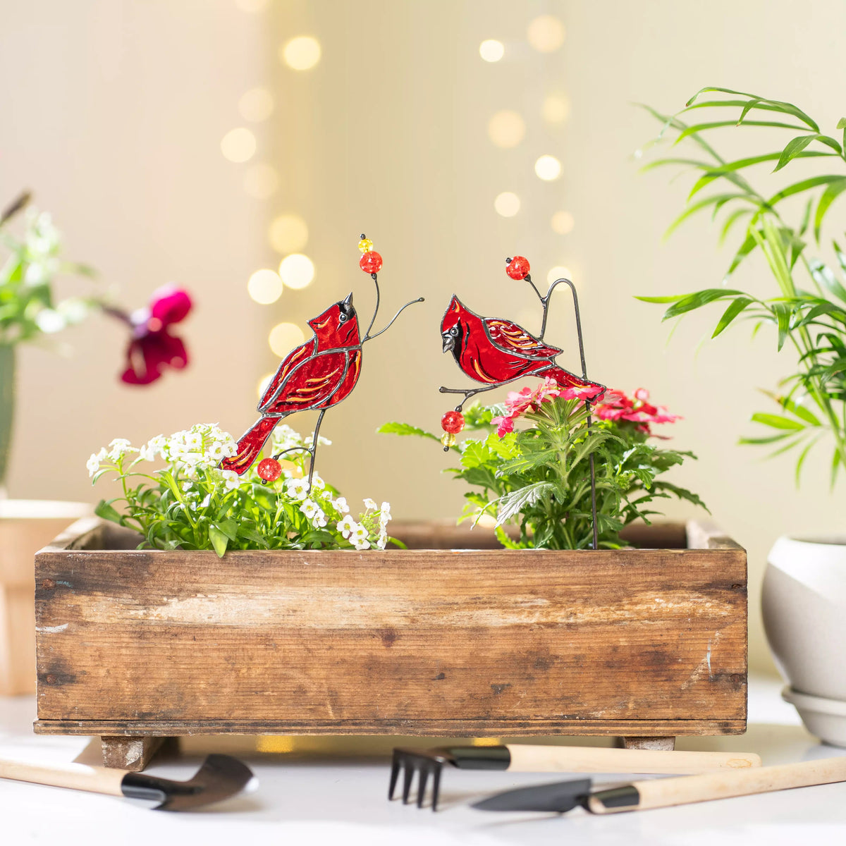 Decorative wooden planter with red cardinal birds and flowers on a blurred background