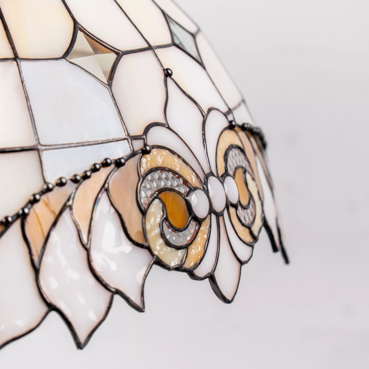 Close-up of decorative bow in amber, ivory, and clear stained glass with fine soldering