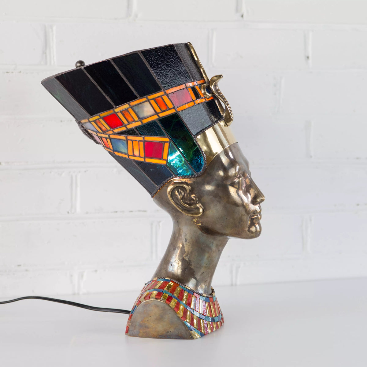 Close-up of stained glass panel showing Queen Nefertiti in profile with rich amber and blue glass