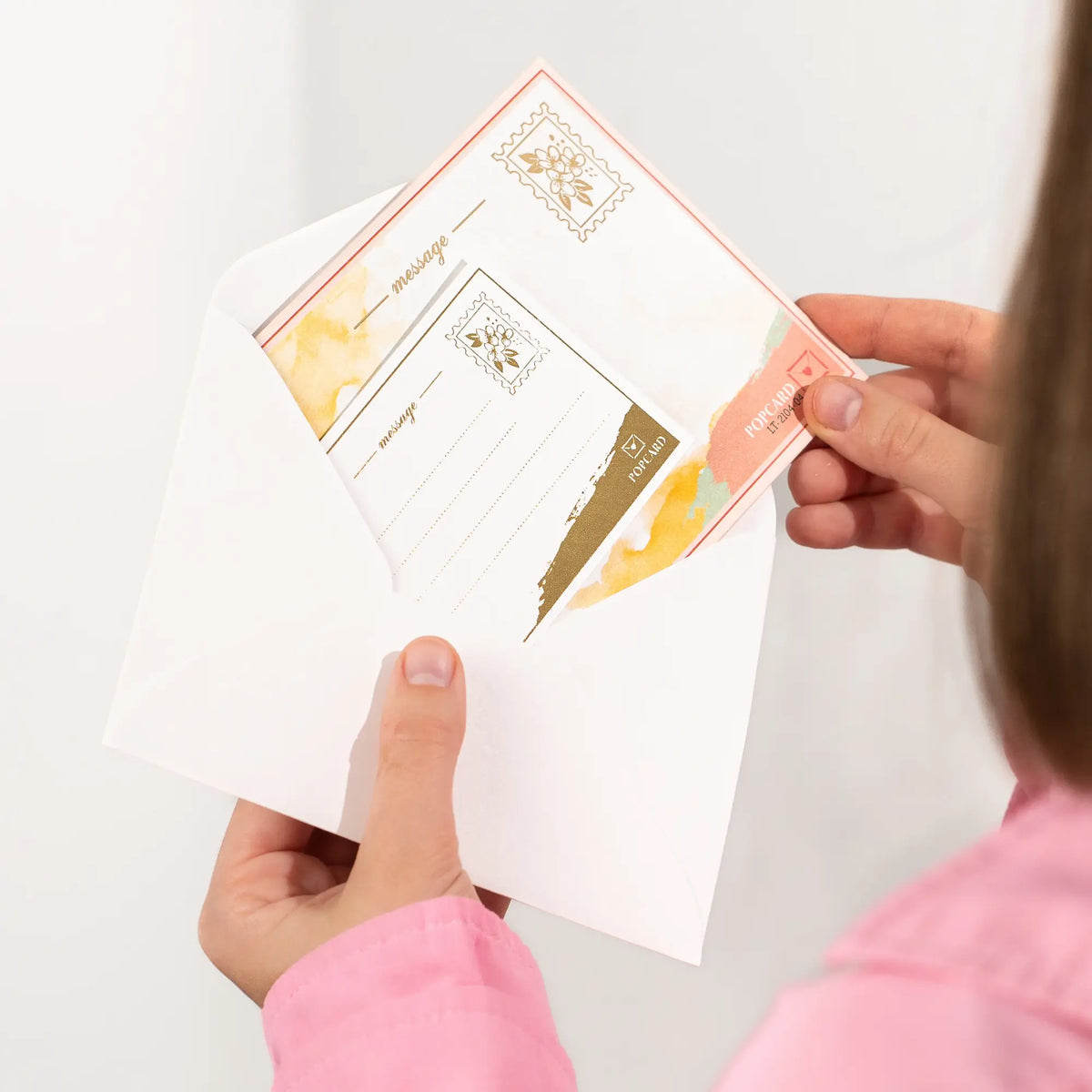 Hands holding a set of envelope and greeting card with a white background