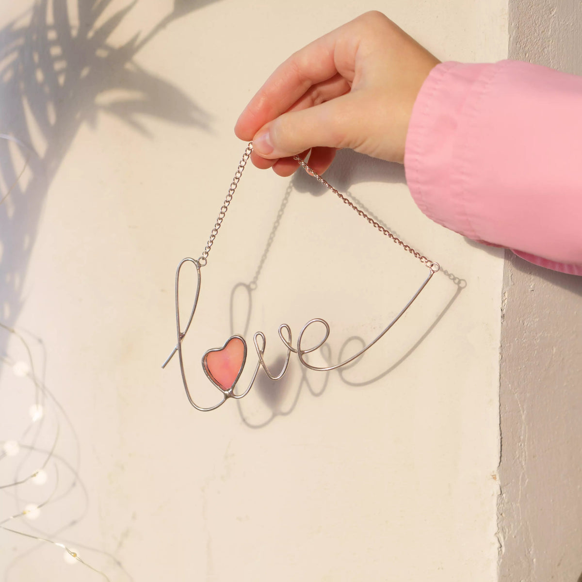 Love stained glass wire sign displayed against a red background, featuring a glowing pink iridescent heart.