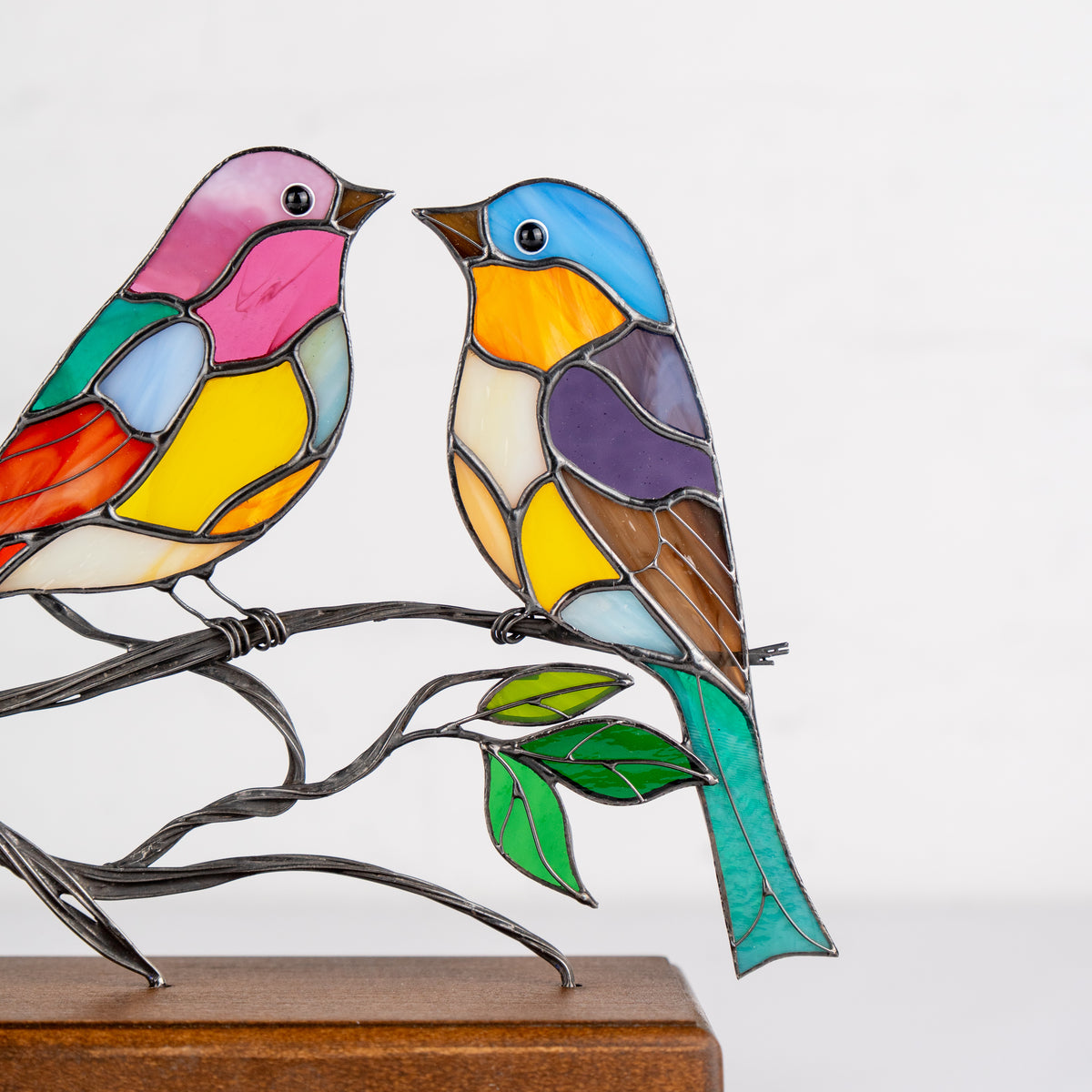 Close-up of rightmost bird in stained glass stand, featuring vibrant blue and purple hues.