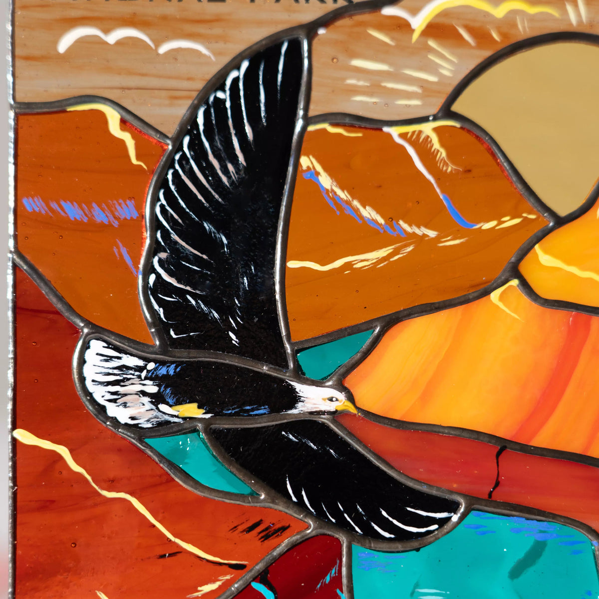 A close-up view of the eagle and canyon details in a handcrafted stained glass panel.