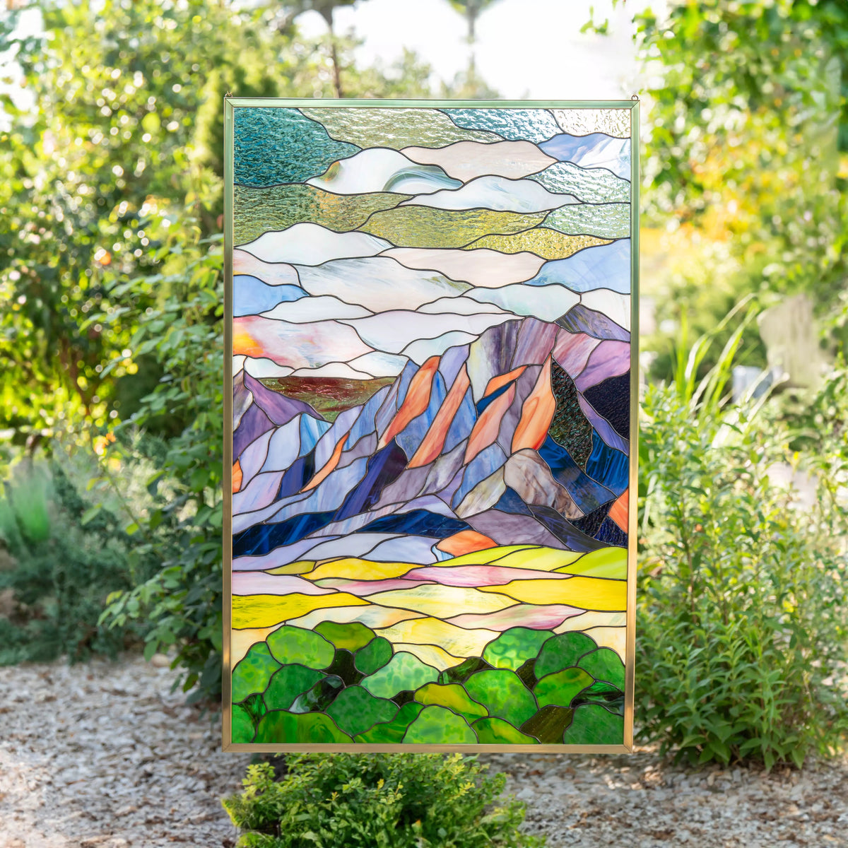 Custom stained glass panel with mountain Flatirons design in a natural setting