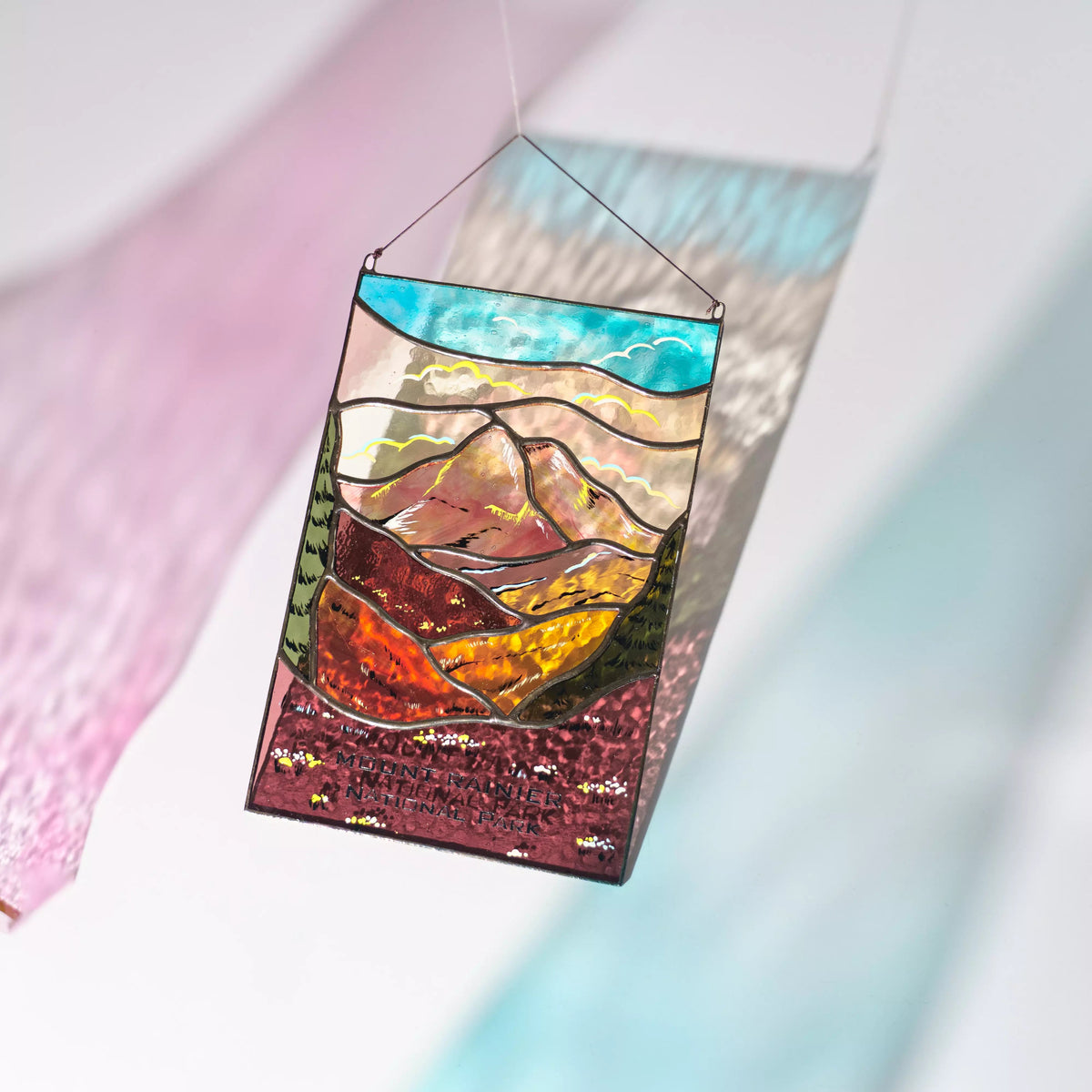 Stained glass panel Mount Rainier, casting a colorful shadow on a light background