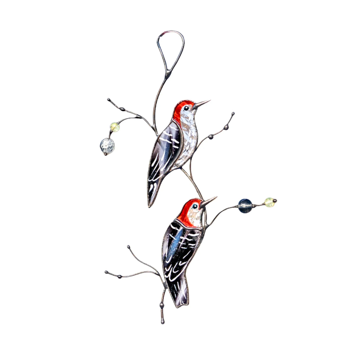 A pair of handcrafted stained glass red-headed woodpeckers with textured black and white wings perched on artistic metal branches, shown against a white background.