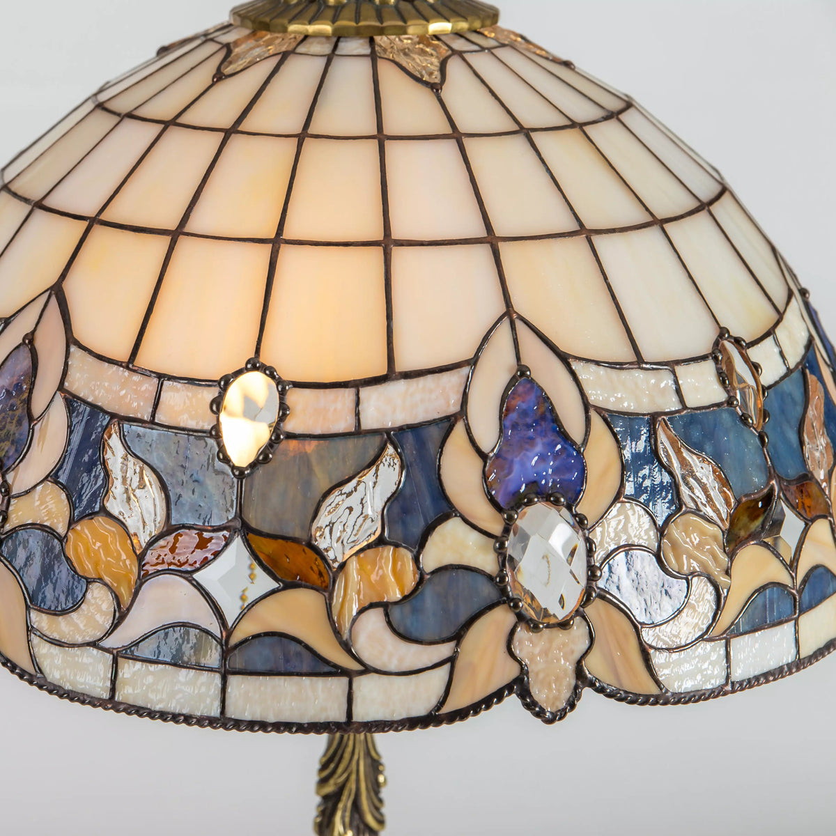 Close-up of stained glass table lamp shade with floral design in blue, amber, and clear glass pieces