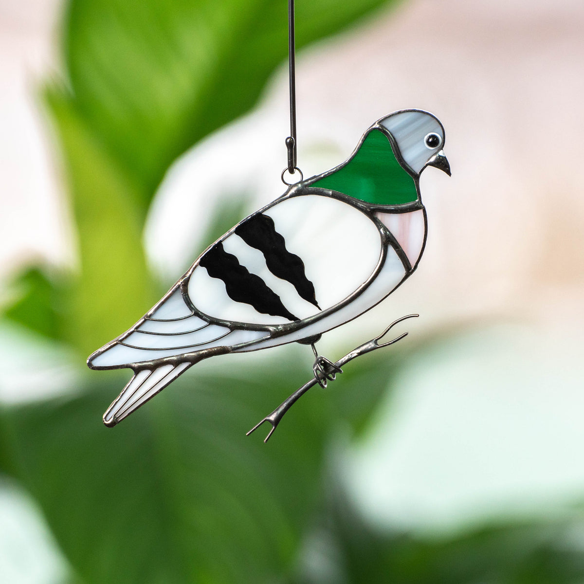 Stained glass window hanging of a pigeon sitting on the branch