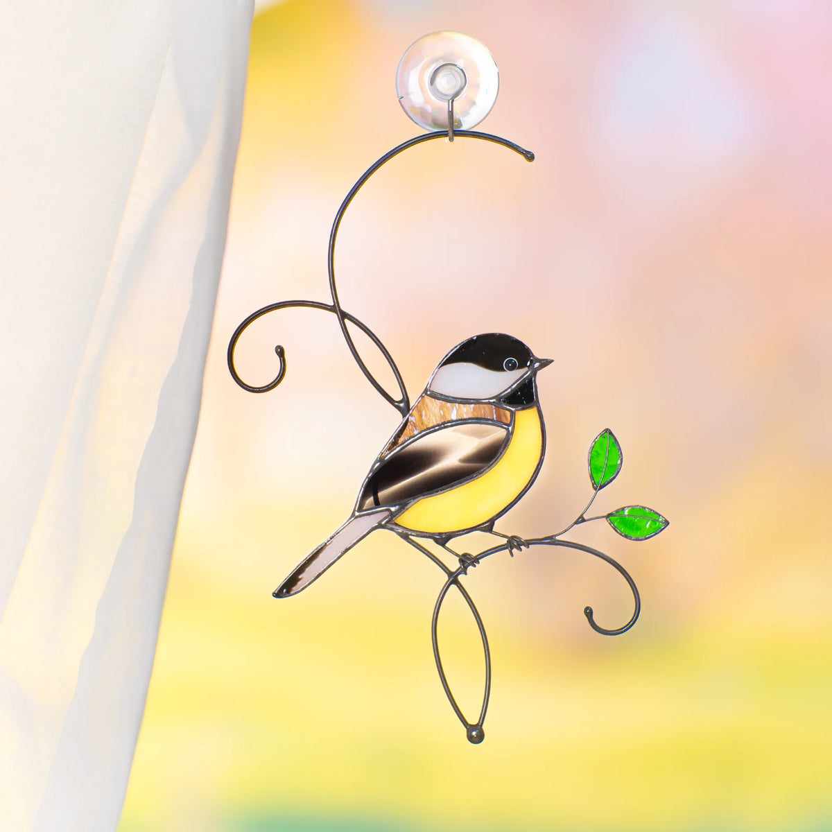 Stained glass chickadee suncatcher on a bright window with a suction cup and sheer curtain, black-capped chickadee with a yellow belly on a wire branch with green leaves - handmade bird window decor