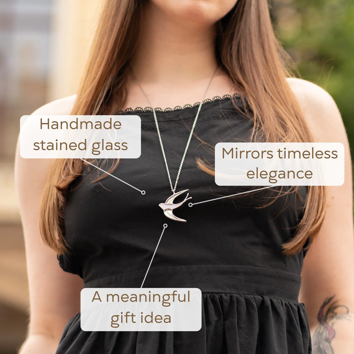 Woman wearing the White Swallow stained glass necklace over a black top - a handmade stained glass jewelry swallow that mirrors timeless elegance and makes a meaningful gift idea