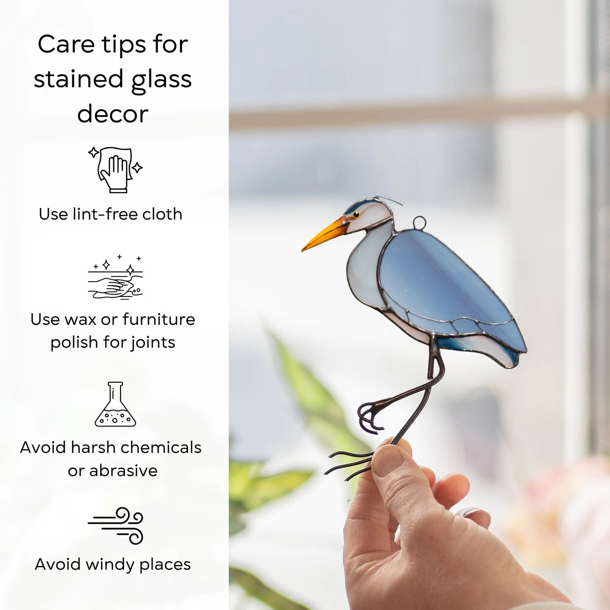 Care tips for stained glass decor beside a blue heron suncatcher held at a window - wipe with a lint-free cloth, wax the joints, avoid harsh chemicals and windy places