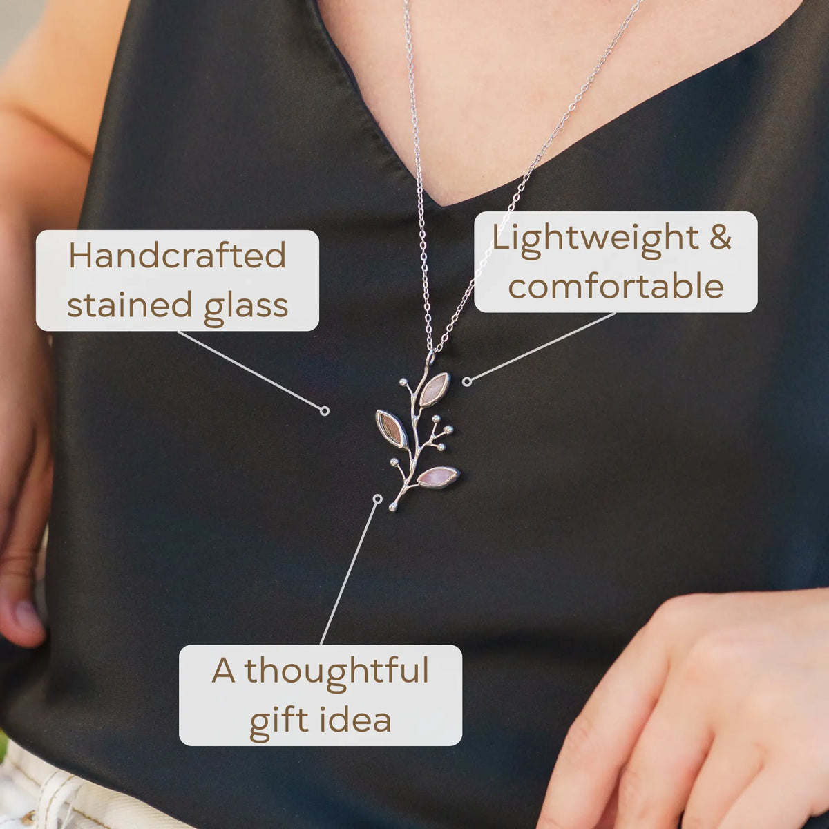 Woman wearing the Pink Buds stained glass necklace over a satin top - a handcrafted stained glass branch pendant that captures and reflects charm and makes a thoughtful gift idea