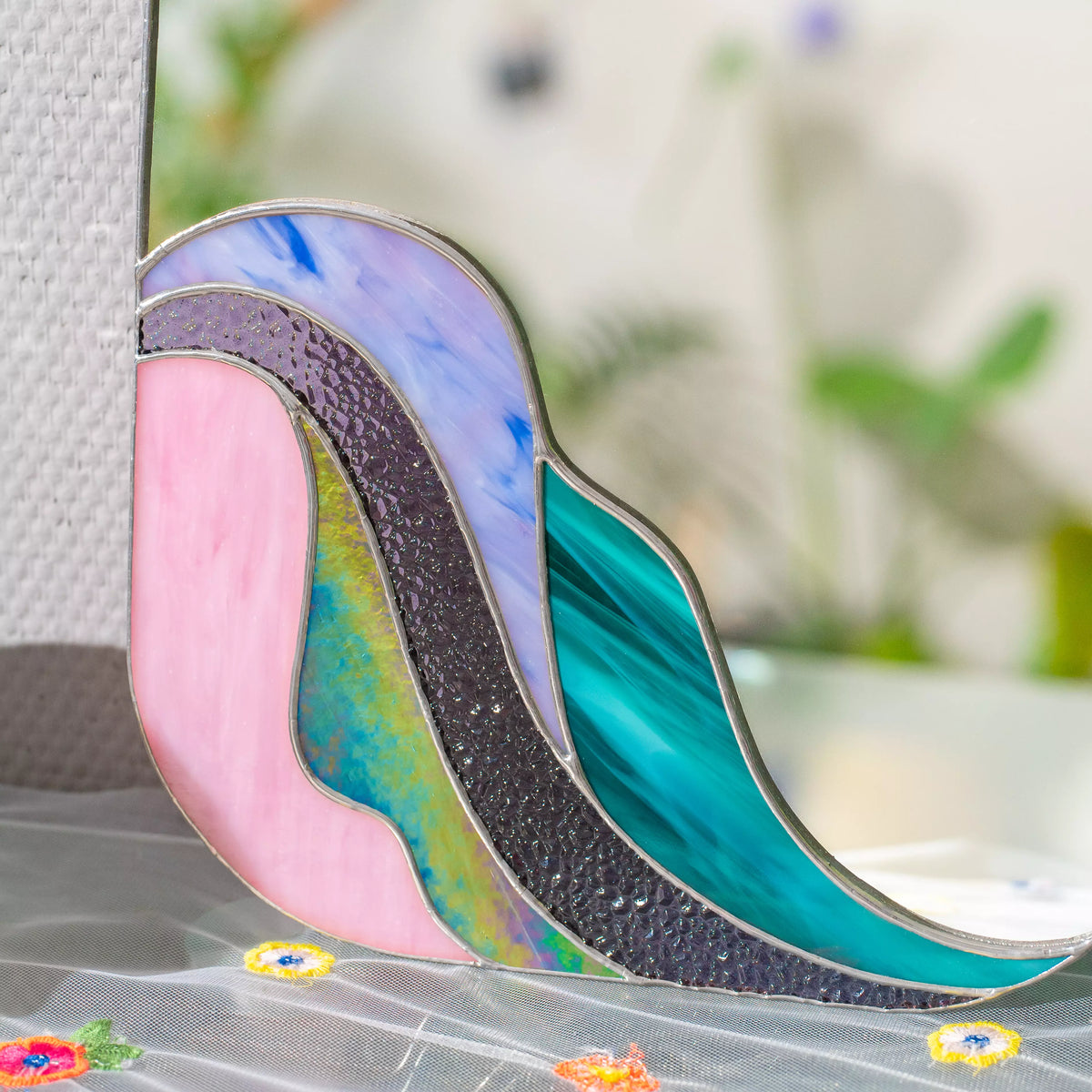 Lifestyle photo of Purple Waves stained glass mirror on a wall, violet cathedral glass and copper foil border catching soft light — handmade home decor by Glass Art Stories