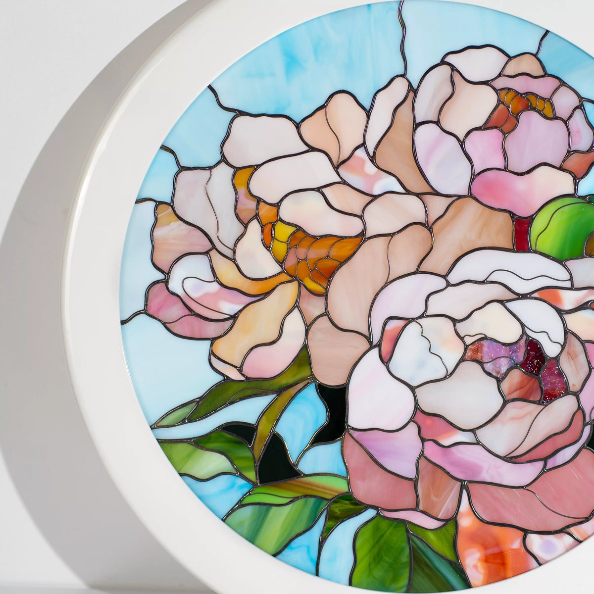 Detail of a pink peony bloom in stained glass with a deep magenta center and layered blush petals and dark patina seams - handmade round framed floral panel and gift for flower lovers