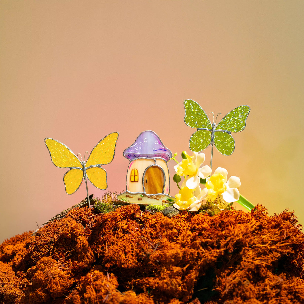 A magical scene of a yellow butterfly, mushroom house, and green butterfly stake set in a mossy, earthy landscape with small yellow flowers.