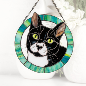 A stained glass window hanging featuring a cat in a circular frame