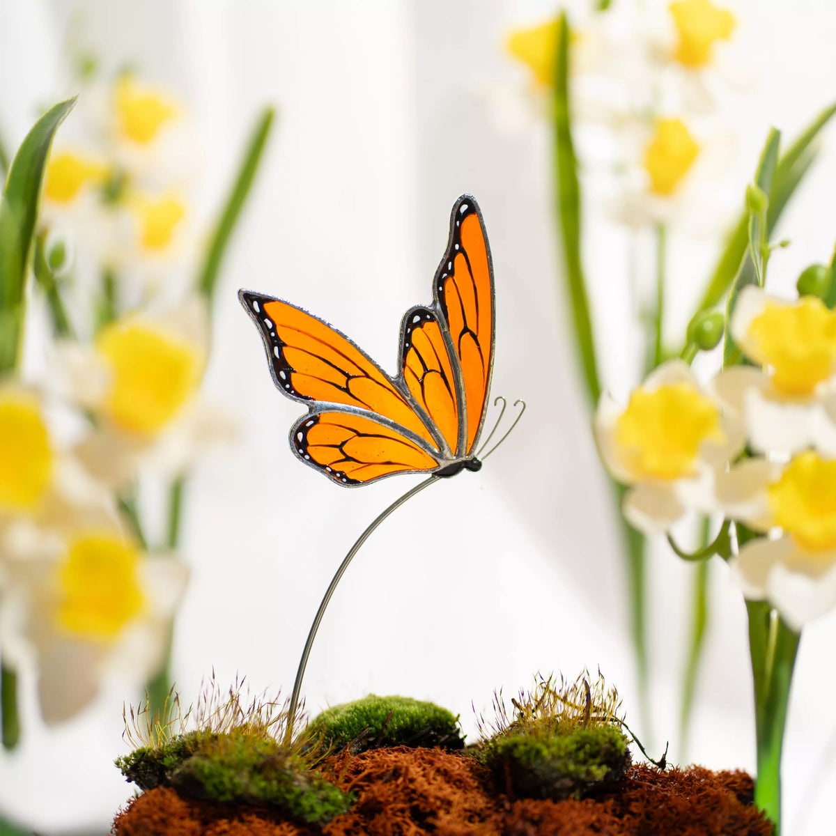 Stained glass butterfly on a branch with a blurred floral background