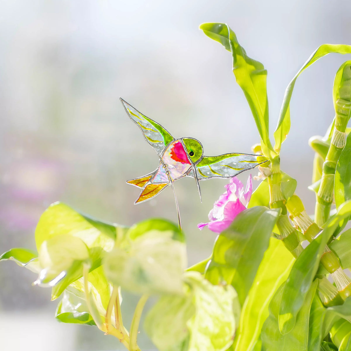 Stained glass hummingbird on a branch plant stake with leaves and flowers