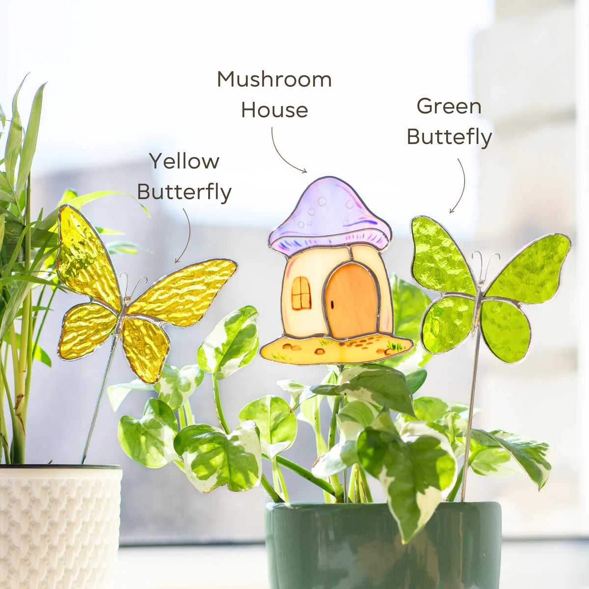Stained glass plant stakes shaped like a mushroom house and butterflies on plants with labels.