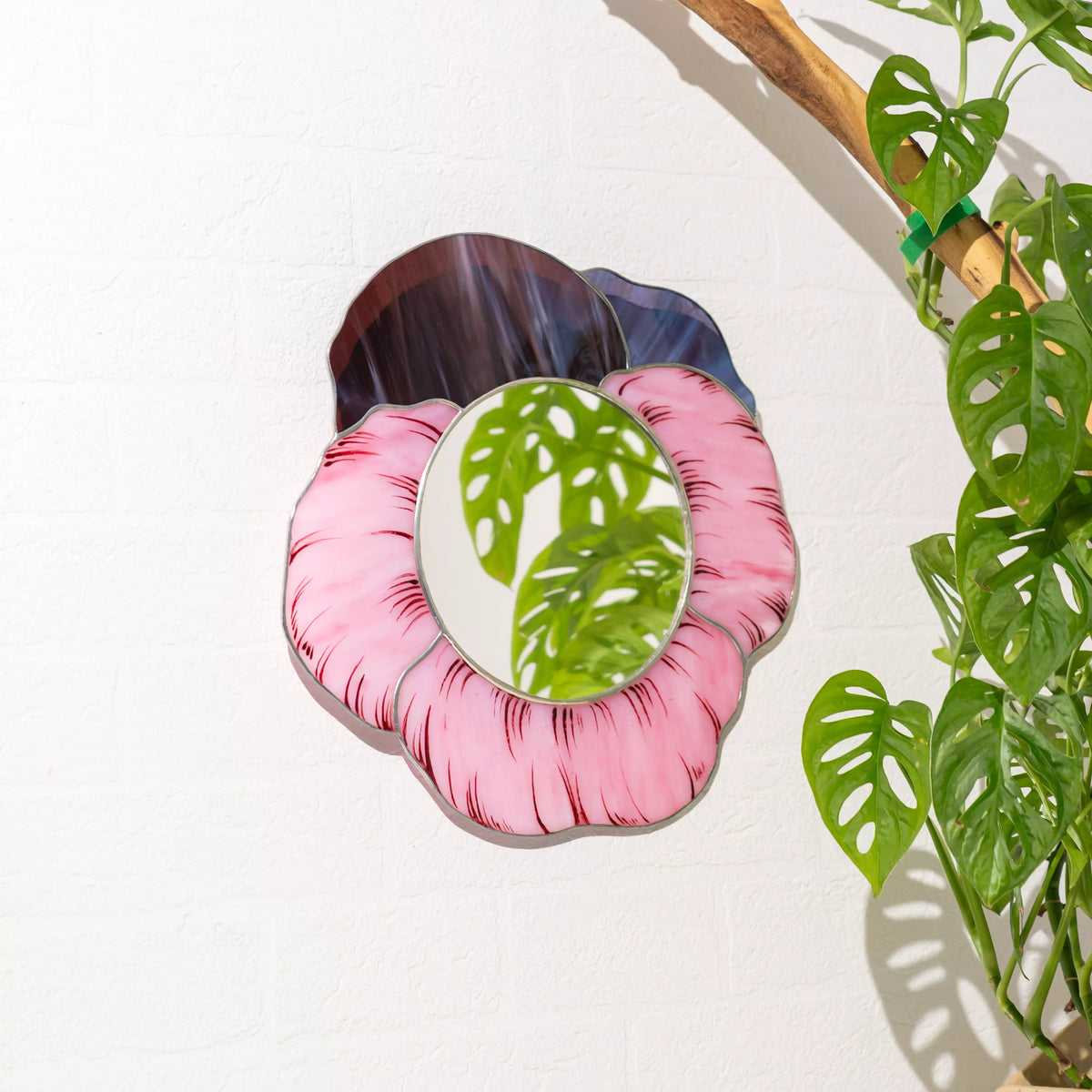 Stained glass mirror with pink floral design on a white background