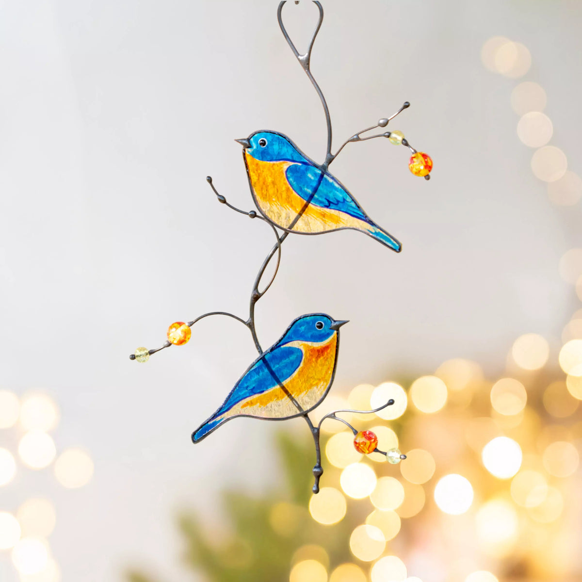 Stained glass bluebirds on a branch with a blurred bokeh background