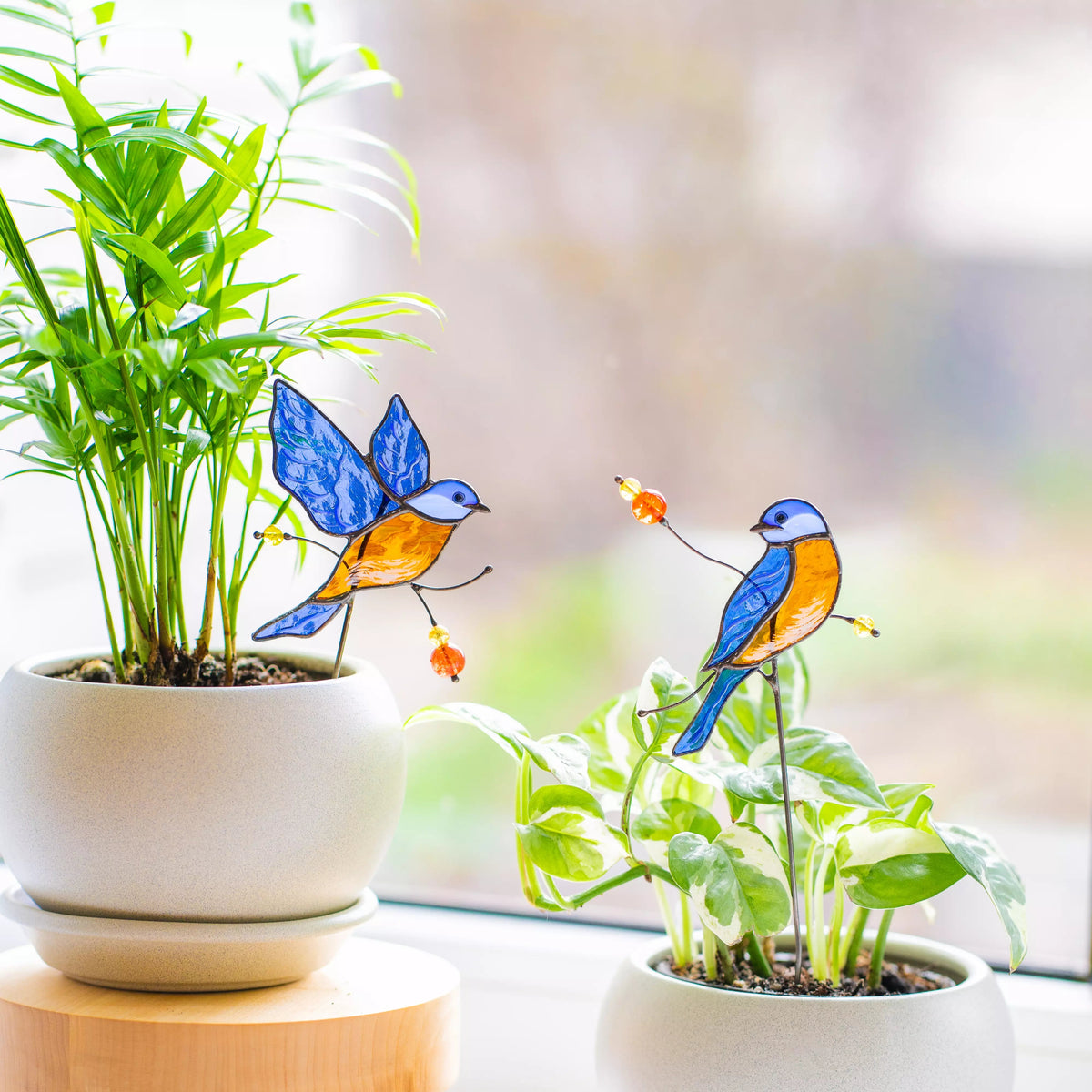 Decorative stained glass bluebirds on plants with a blurred background