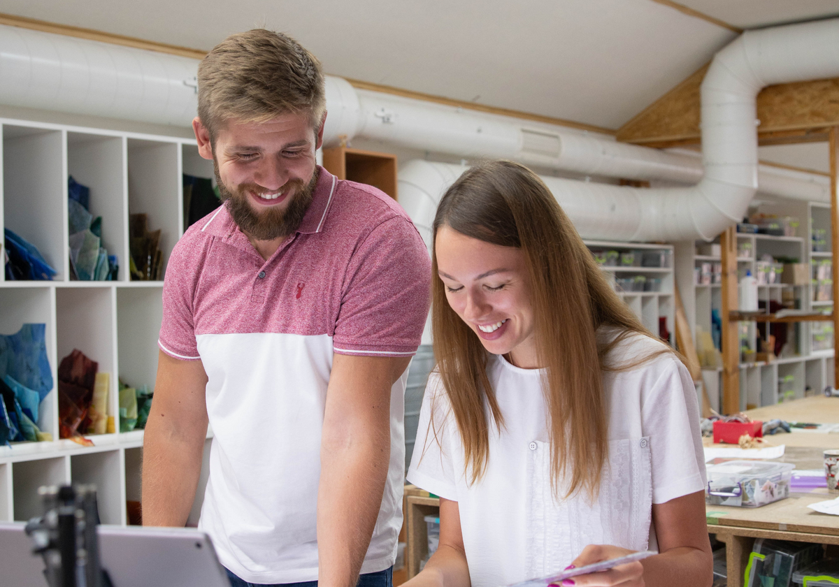 Man and woman smiling while working together in a creative workshop