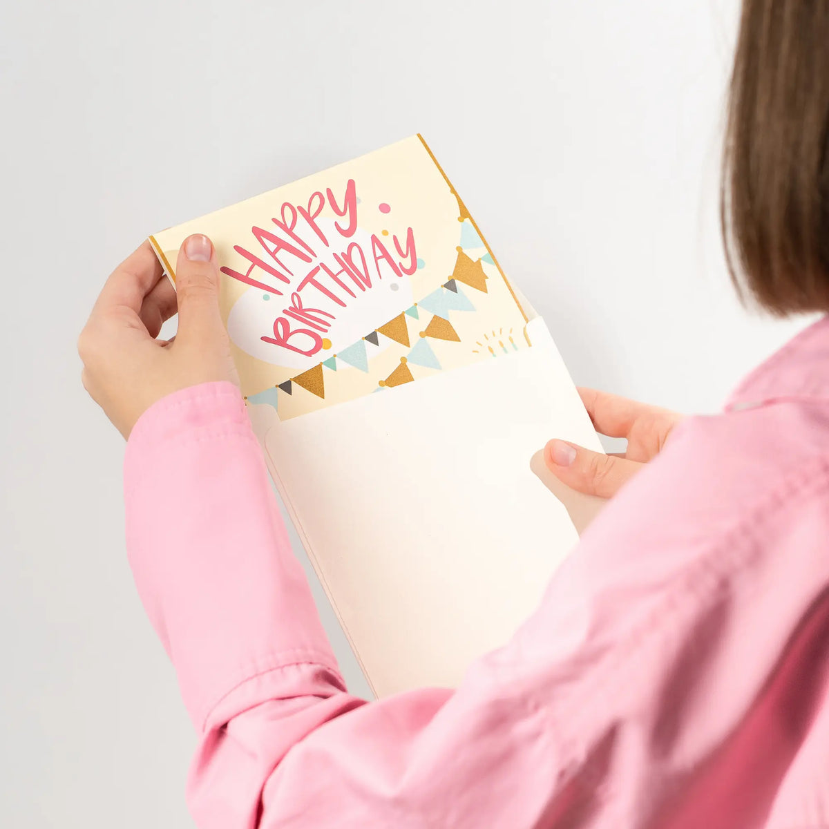 Women holding a birthday card with 'Happy Birthday' text on a plain background
