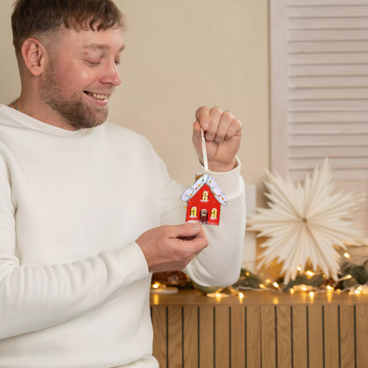 Person holding stained glass suncatcher red gingerbread house ornament
