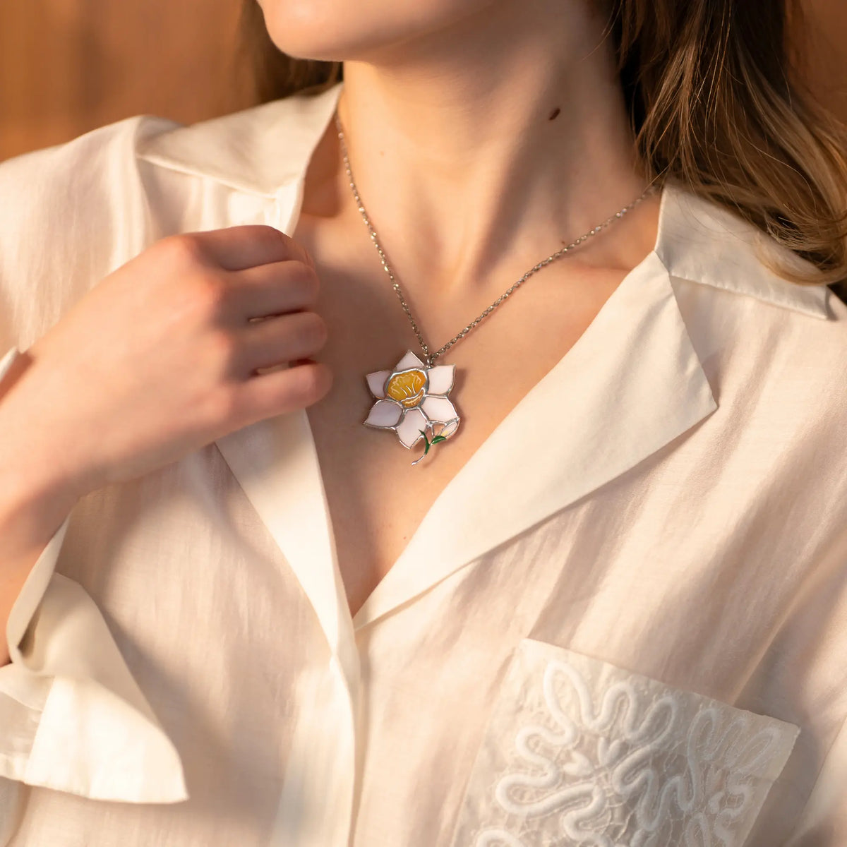 Women wearing a white blouse with a floral daffodil stained glass necklace