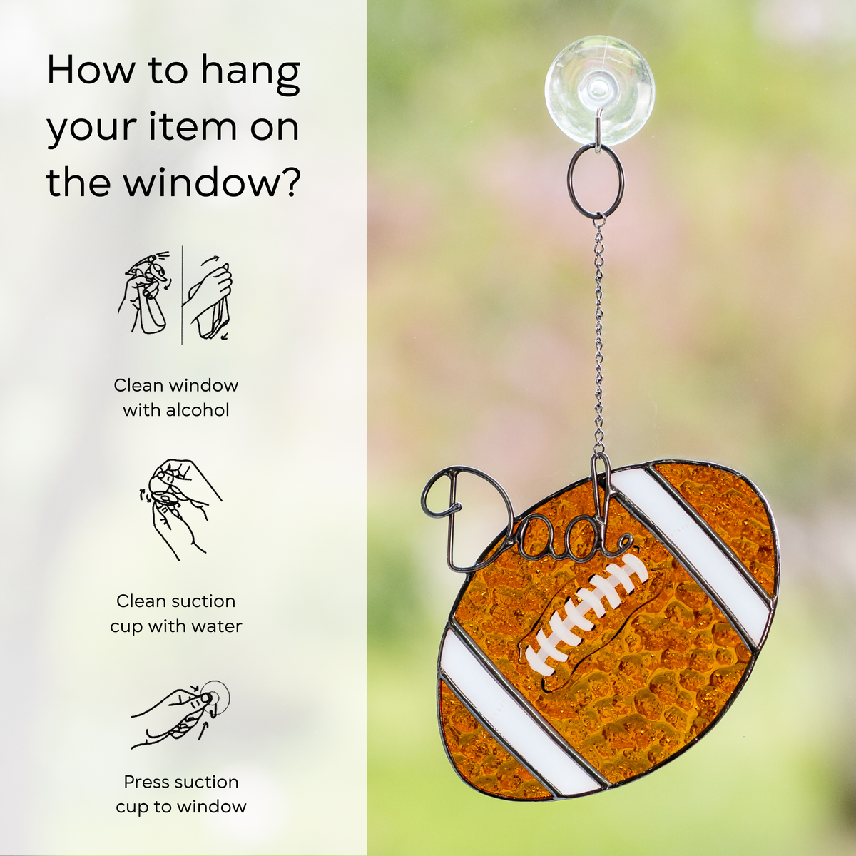 Suncatcher rugby ball hanging on a window using a suction cup, with care instructions shown: clean window and suction cup, press a cup to the surface.