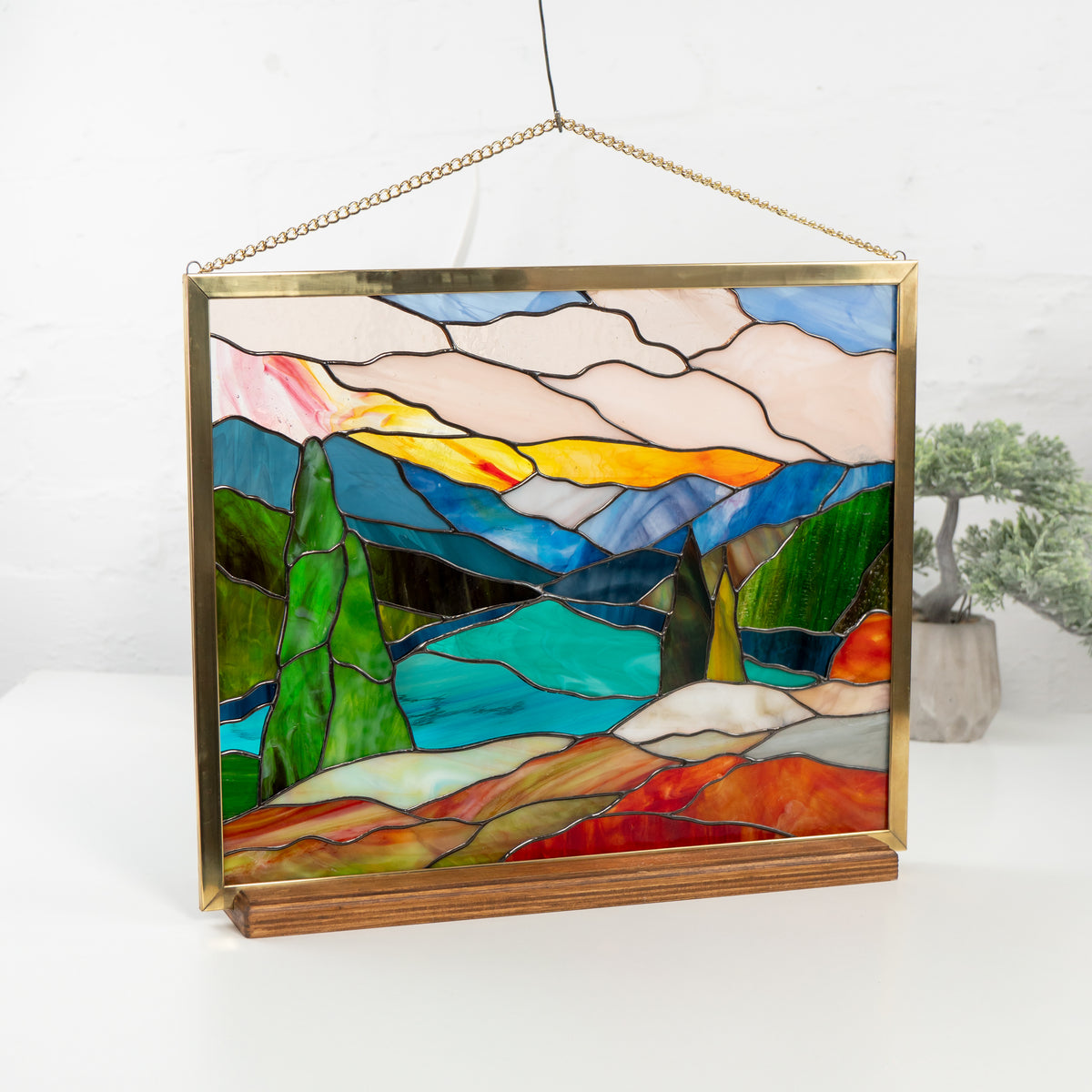 Angled image of Mount Rainier stained glass panel on display with mountains, trees, and lake scene