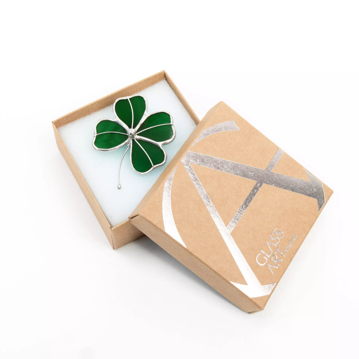 Green stained glass four-leaf clover brooch in a brown box with silver Glass Art Stories logo