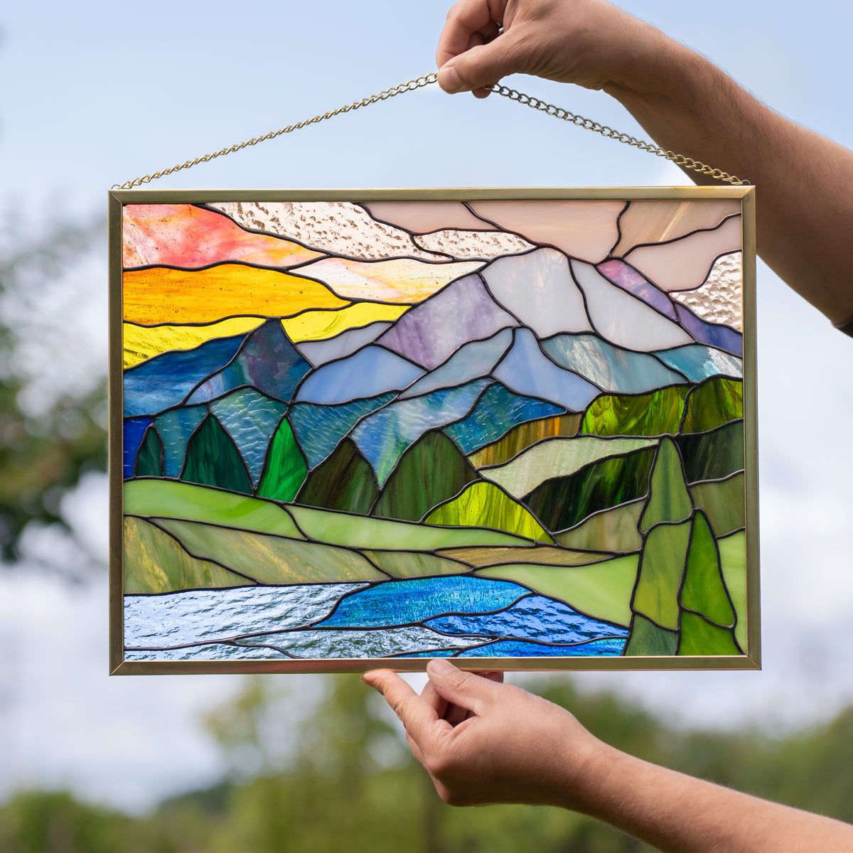 Hands holding stained glass panel with Glacier National park