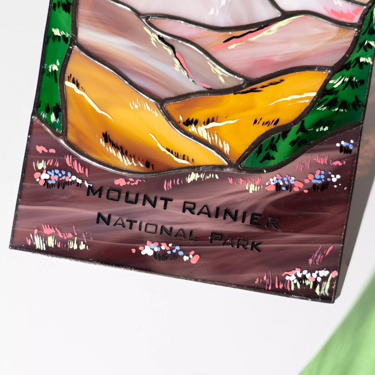 A close-up view of the Mount Rainier National Park engraving on a handcrafted stained glass landscape panel.