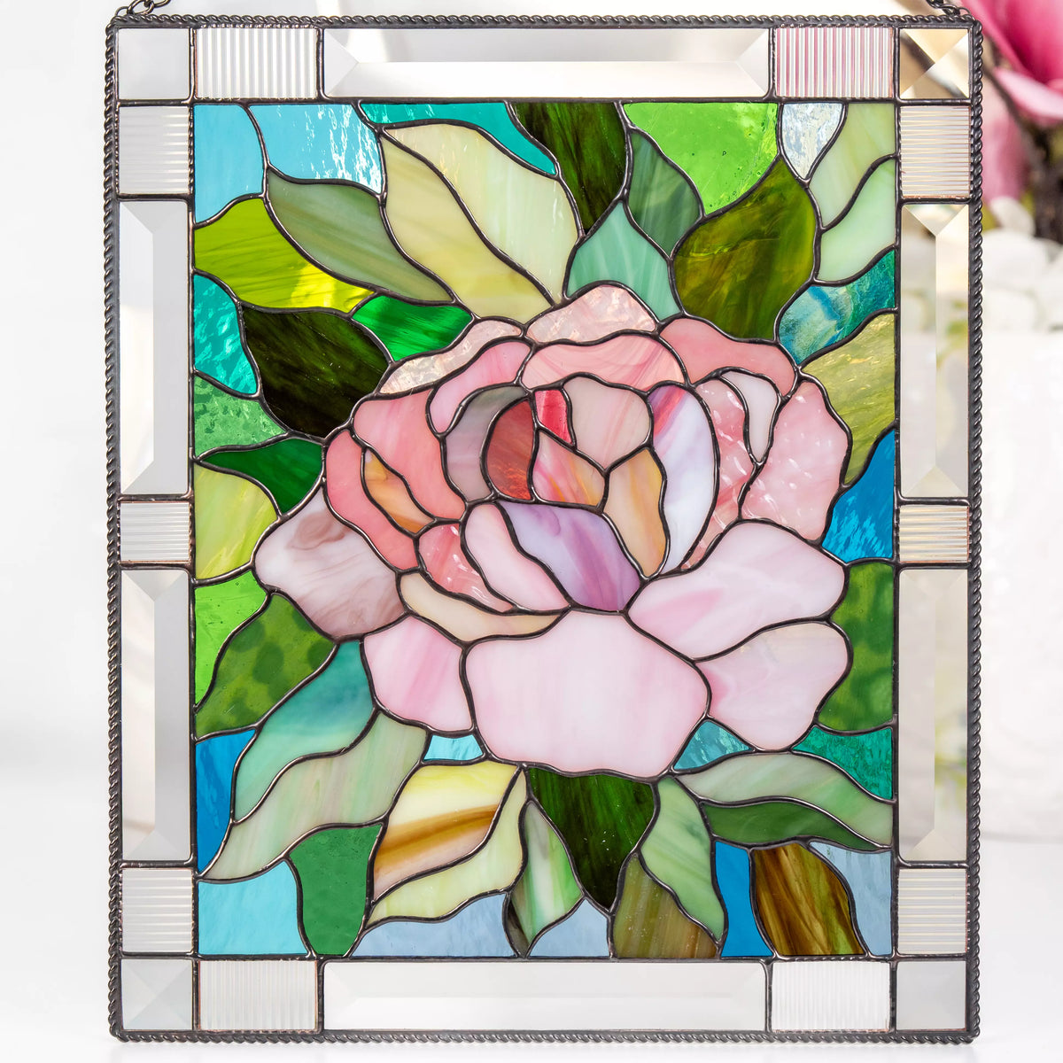 Stained glass panel with a pink peony and green leaves