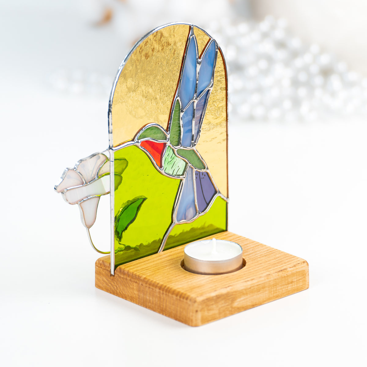 Candle-lit stained glass panel in a wooden base from behind