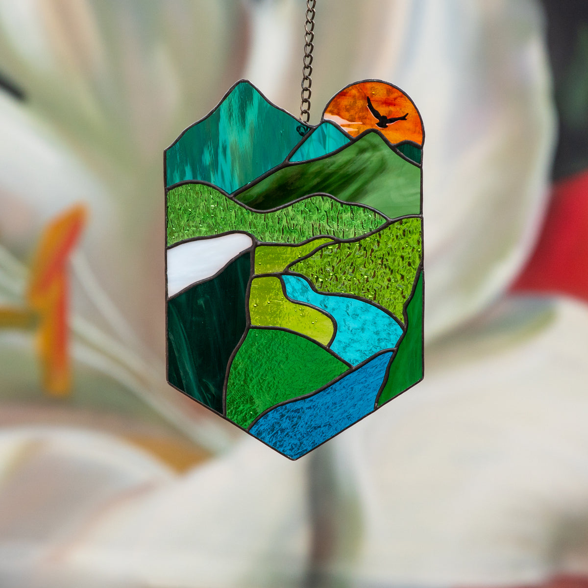 Bright stained glass panel depicting nature and the orange sun
