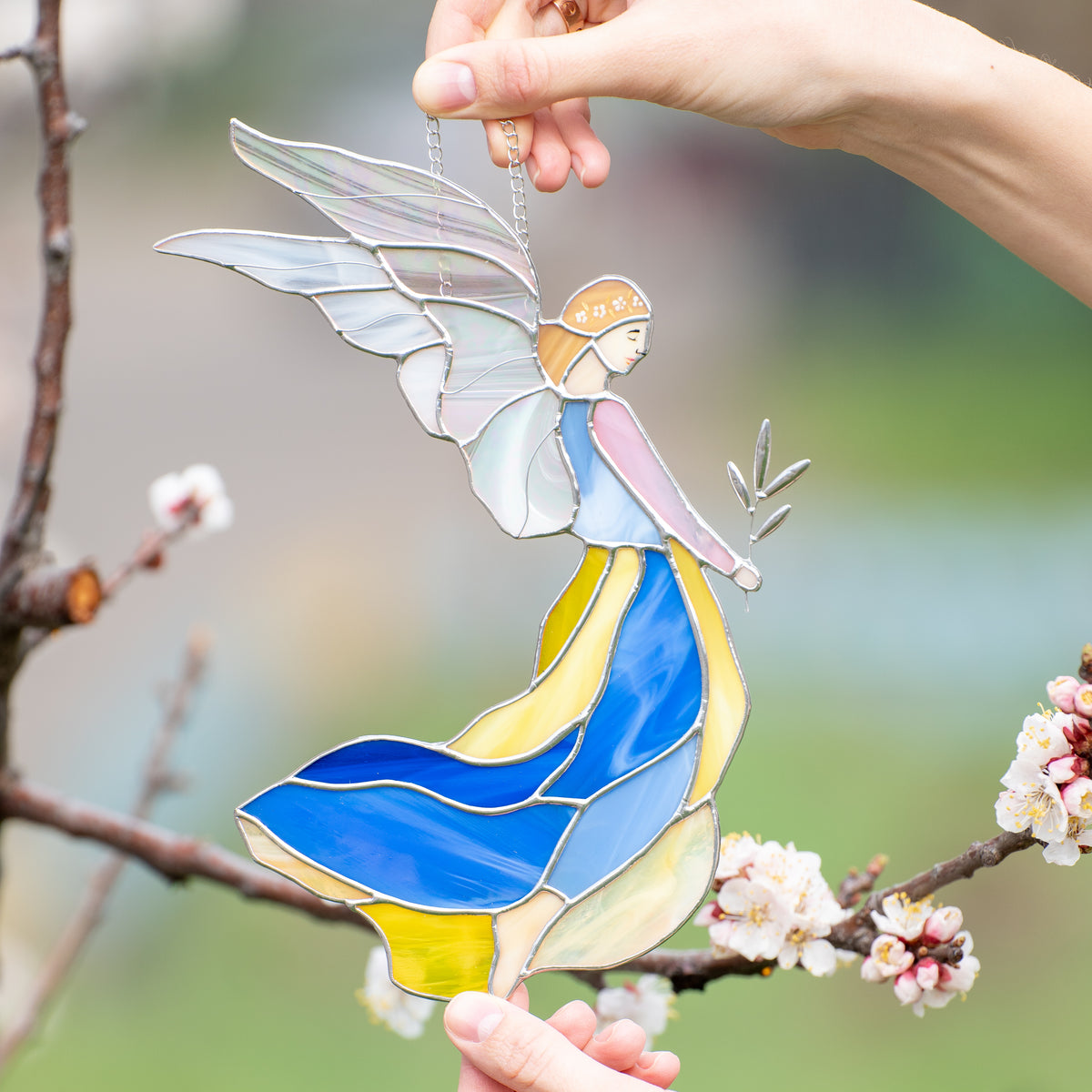 Zoomed stained glass girl guardian angel in blue and yellow dress with iridescent wings 