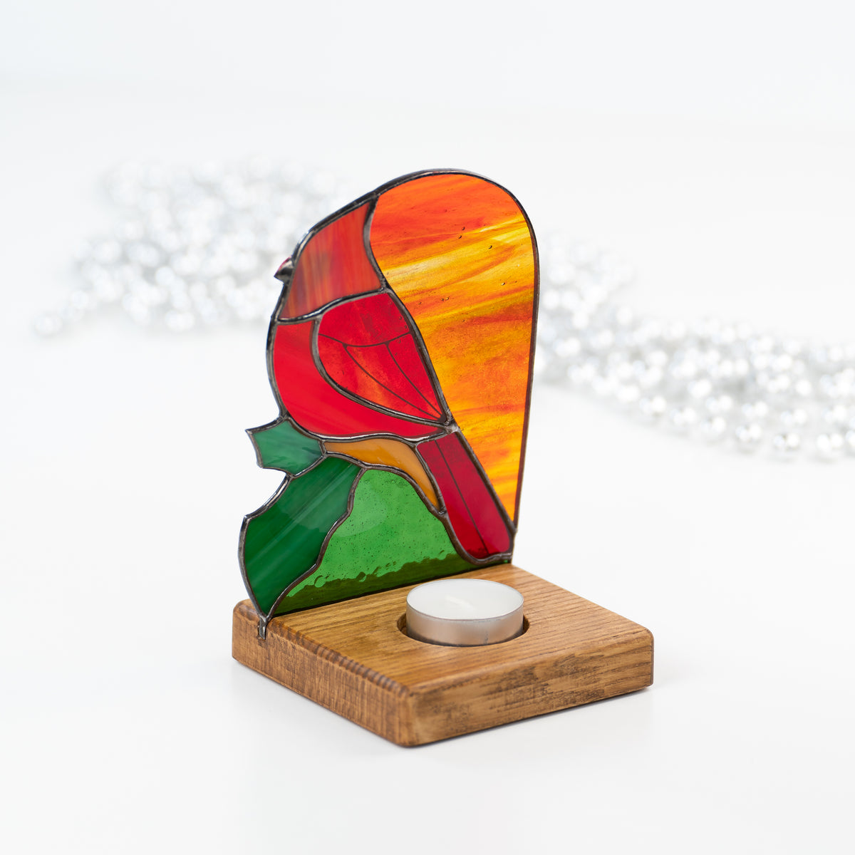 Candle-lit red cardinal panel in a wooden base from behind